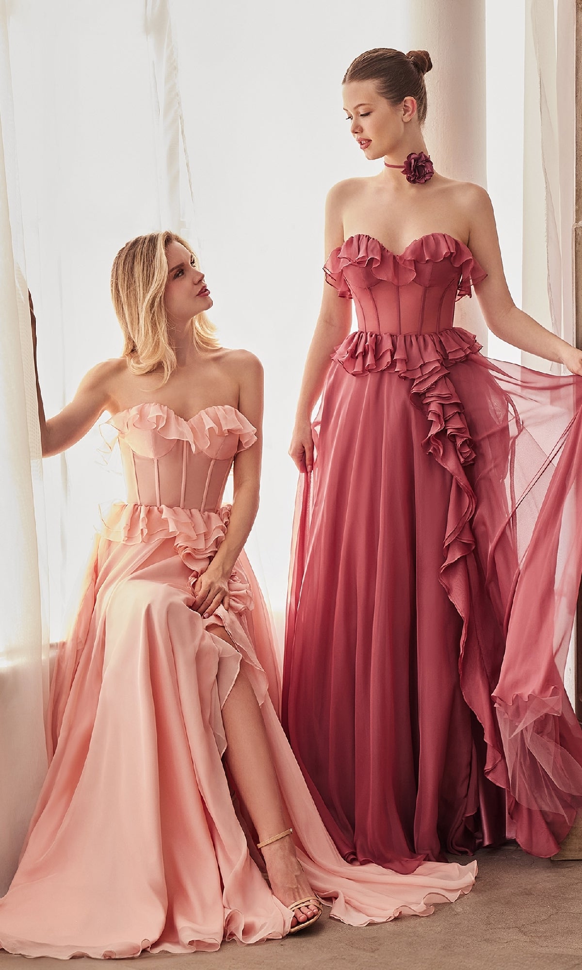 Two women wear the Andrea and Leo A1341 Strapless Ruffled Prom Dress in pink and mauve, posing by a window illuminated with soft natural light.